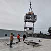 Guiding crane loaded with rooftop unit into place